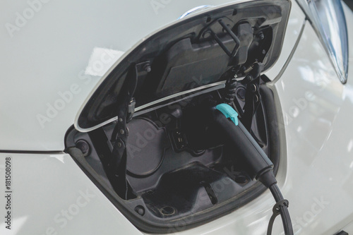 View of electric car plugged in for recharging. Electric car energy station, vehicle refilling.