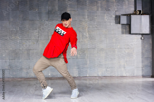 Young freestyle dancer on grey background. Young bold rap dancer in action on grey studio background.