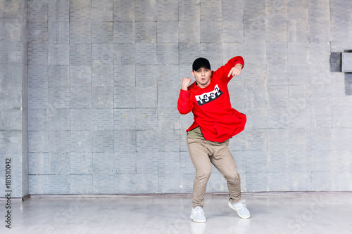 Young stylish man dancing hip-hop. Attractive hip-hop guy dancing on grey background. Street style dancing.