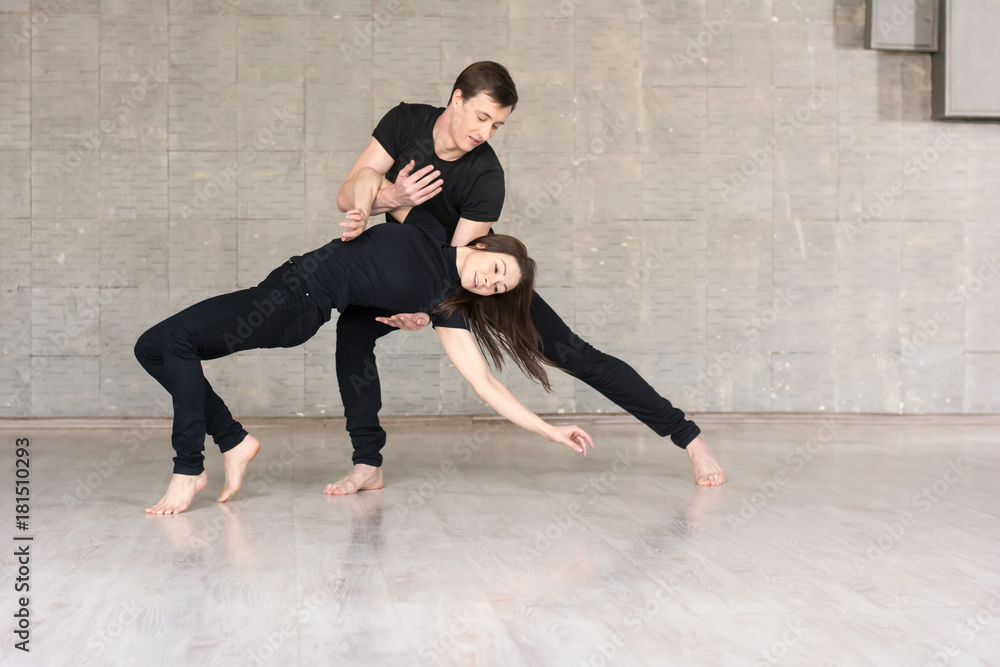 Beautiful couple dancing social dance. Young skillful dancers performing modern dance on grey studio background.