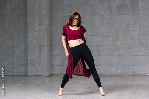 Young slim dancer posing in studio. Young modern style dancer posing on grey studio background. Fitness school of modern dance.