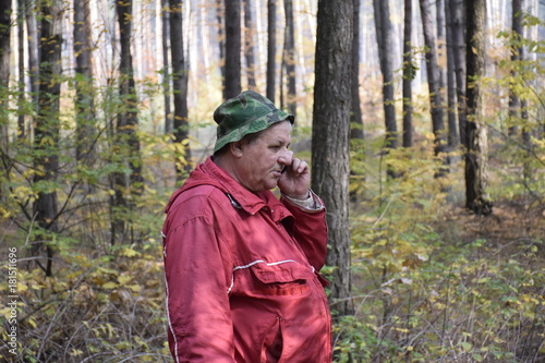 кавказский мужчина разговаривает по телефону в осеннем лесу 