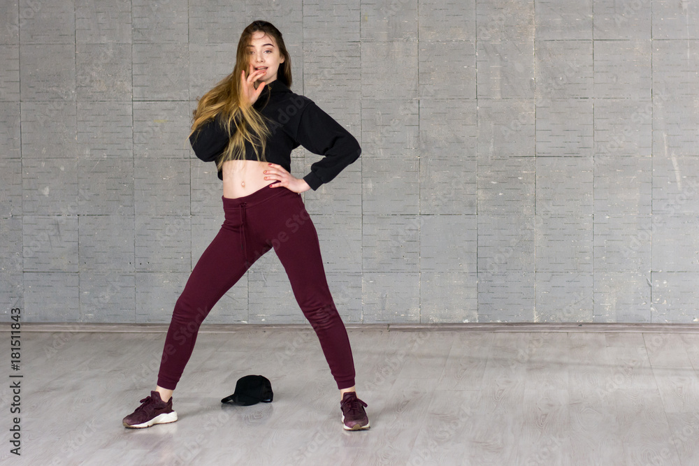 Young female hip-hop dancer. Beautiful young modern style dancer with long hair practicing dance element on studio background. Young female hip-hop dancer. Beautiful young modern style dancer with long hair practicing dance element on studio background.