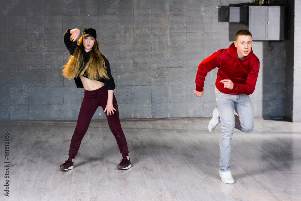 Fototapeta premium Couple of talented dancers performing hip-hop. Guy and girl dancing contemporary dance i studio. School of hip-hop culture.