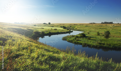 Sunny summer landscape with river.Green meadows and fields at sunrise. © valeriy boyarskiy