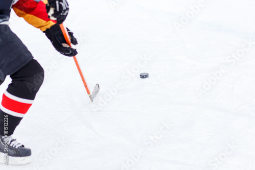 Canvas Print Ice hockey player with stick hitting the puck on rink