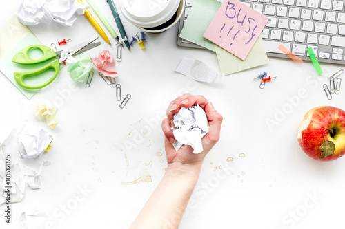 Deadline in office. Hand crumple papaer. Sticker Busy on desk covered with crumpled paper and stationery on white background top view
