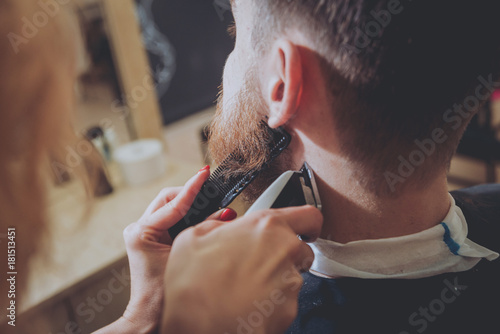 Master cuts hair and beard of men, hairdresser makes hairstyle for a young man. Hipsters