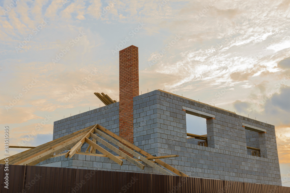 frame of a house under construction from blocks with a roof and a fence frame of a house under construction from blocks with a roof and a fence