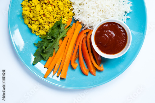 Top view of diet food ketchup and vegetables with a fork next to a blue plate on a white background. photo