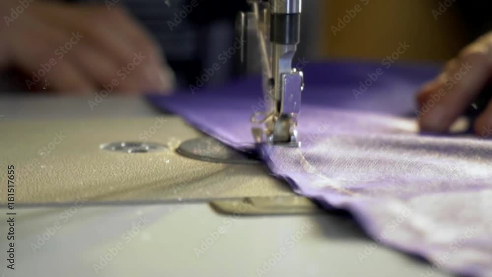 A woman sews a purple cloth on a sewing machine A woman sews a purple cloth on a sewing machine