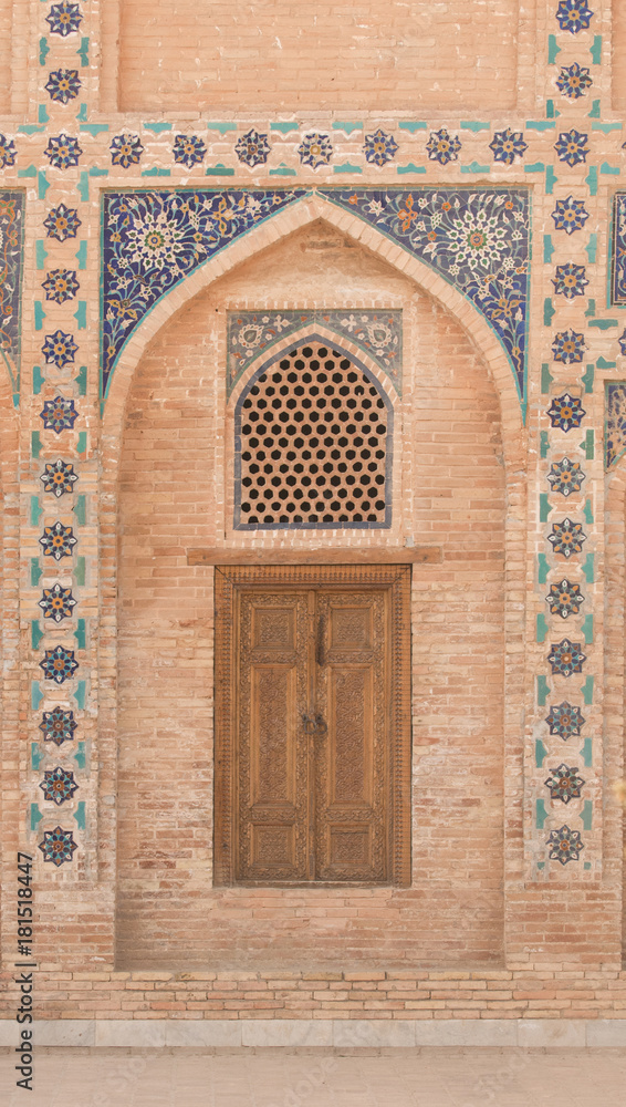 Wooden door with ancient traditional Asian ornamentation and mosaics. the details of the architecture of medieval Central Asia