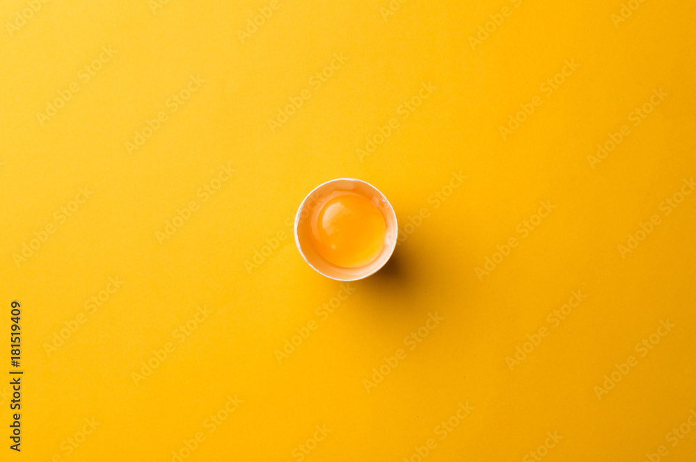 White egg and egg yolk on the yellow background. topview - obrazy, fototapety, plakaty 