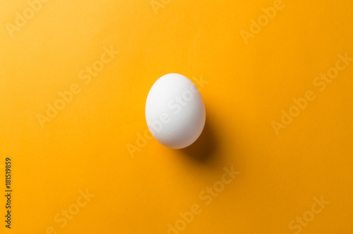 Vászonkép White egg and egg yolk on the yellow background. topview