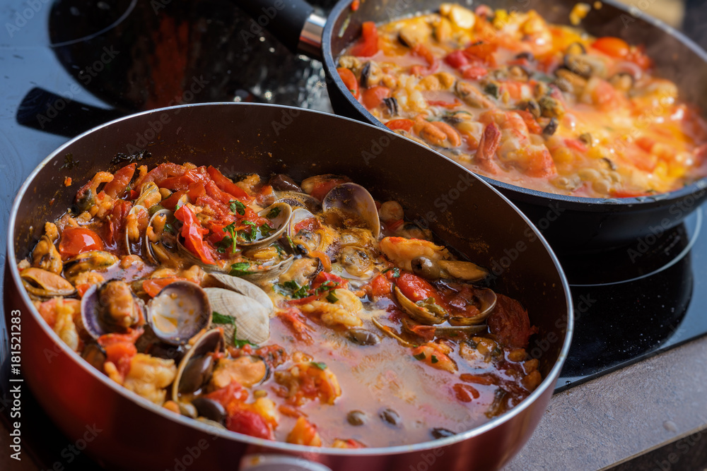 Close-up of frying pans with seafood dish cooked in tomato sauce. Fresh stewed Clams, Shrimps, mussels and squid, base for Italian pasta