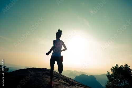 fitness woman runner running on sunrise mountain top edge