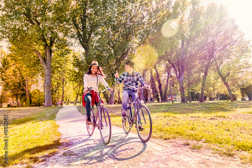 young couple riding bicycles in colorful autumn in park