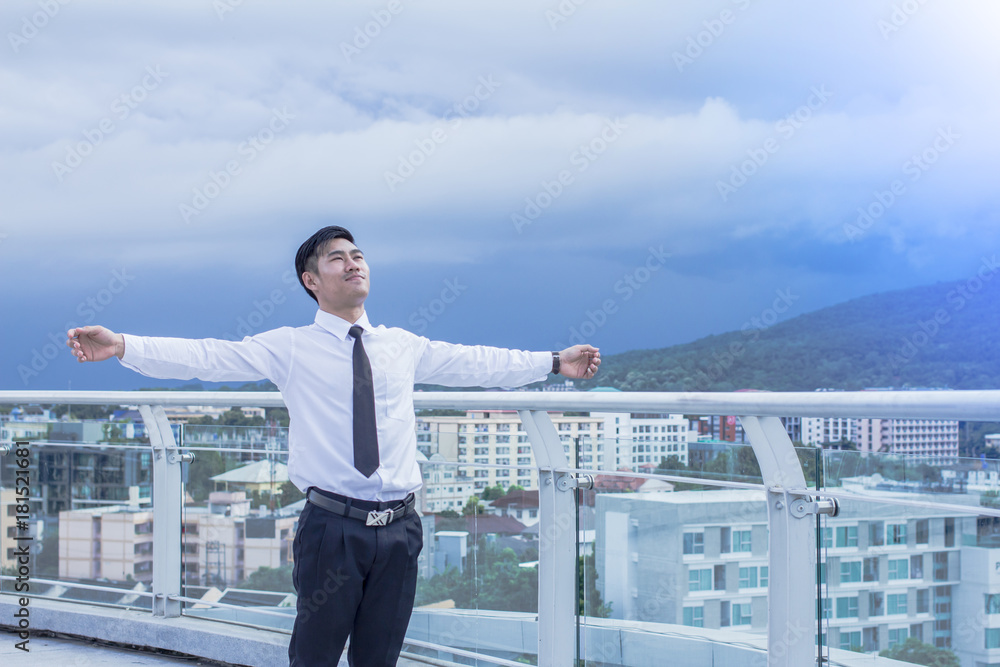 Young Asian Businessman in white shirt Looking up the Sky with Wide Open Arms, Standing at the Open Field.Before holiday vacation new year Young Asian Businessman in white shirt Looking up the Sky with Wide Open Arms, Standing at the Open Field.Before holiday vacation new year