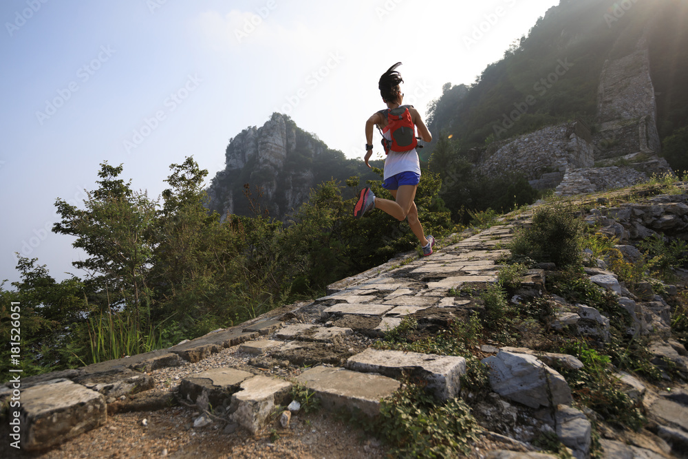 fitness woman trail runner running at great wall on the top of mountain