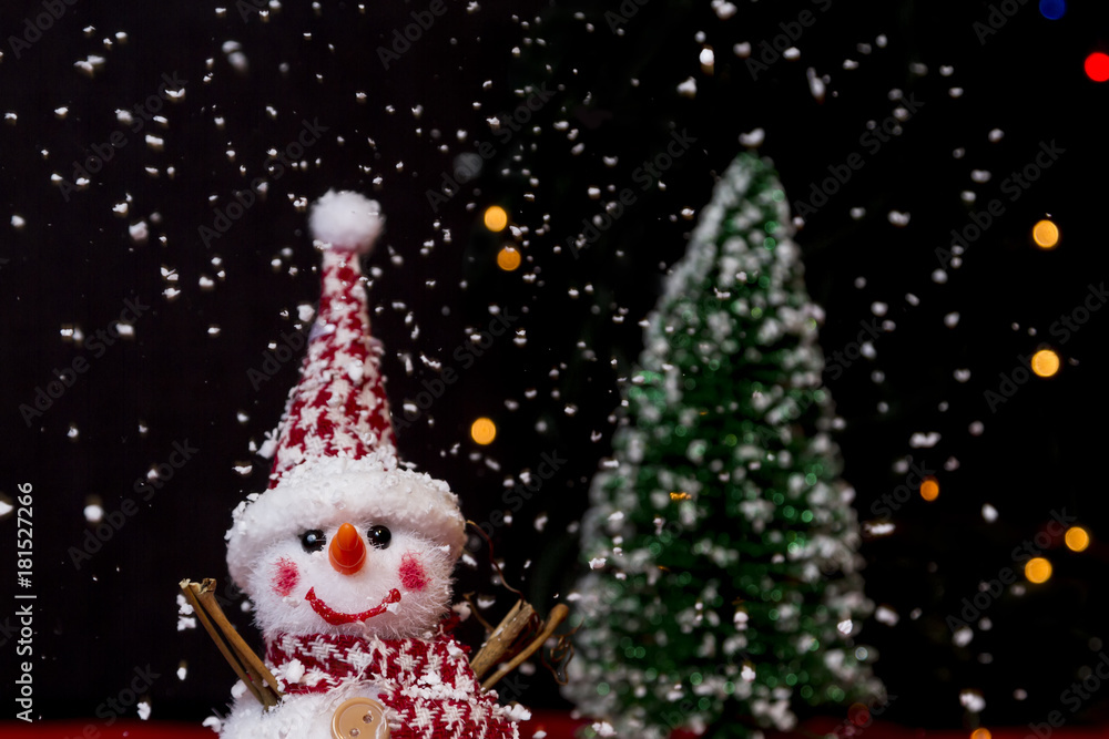 Snowman on snow over blurred christmas tree and light bokeh Snowman on snow over blurred christmas tree and light bokeh