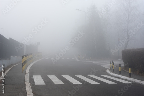 Pedestrian on empty road covered with fog