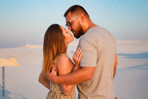 lovely attractive couple kissing on the white sand beach or in the desert or in the sand dunes, happy couple embracing at the beach on a sunny day, couple in love