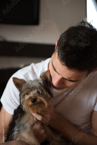 Young man in white shirt cuddling with Yorkshire terrier