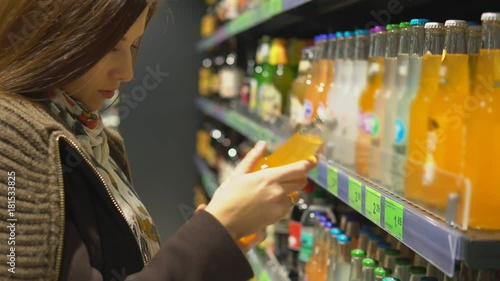 A woman is buying a drink in a bottle in a store.