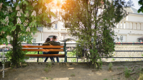 loving couple sitting in a park near the river in autumn