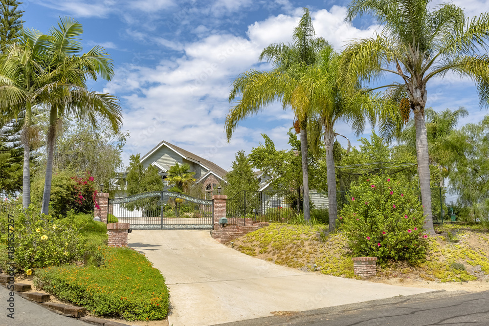 Fototapeta premium California home with gate below puffy clouds and blue skies