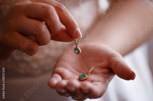 Bride keeps earrings with green precious stones