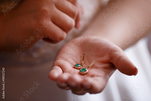 Bride keeps earrings with green precious stones
