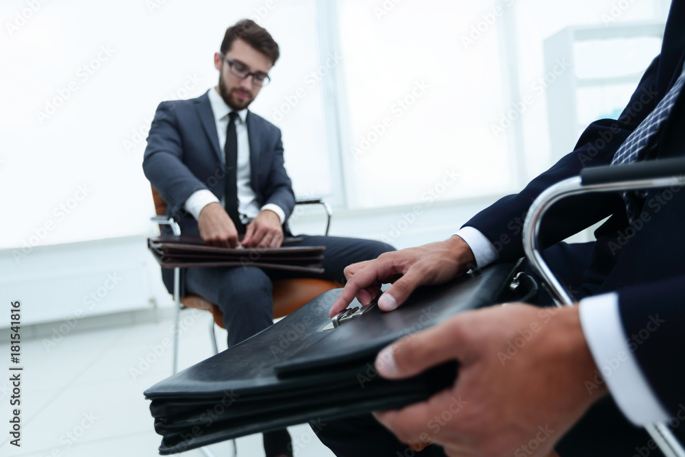 Man in a classic suit holds a brown briefcase close-up Man in a classic suit holds a brown briefcase close-up