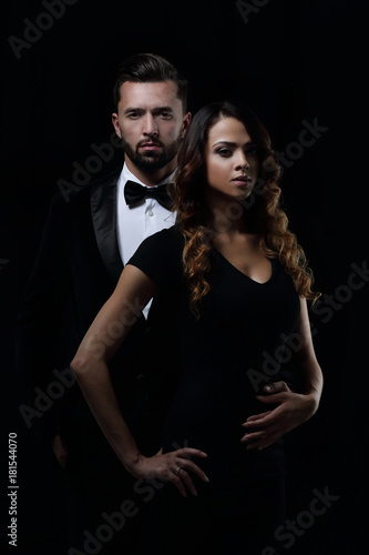 elegant man and woman posing next to each other on studio.