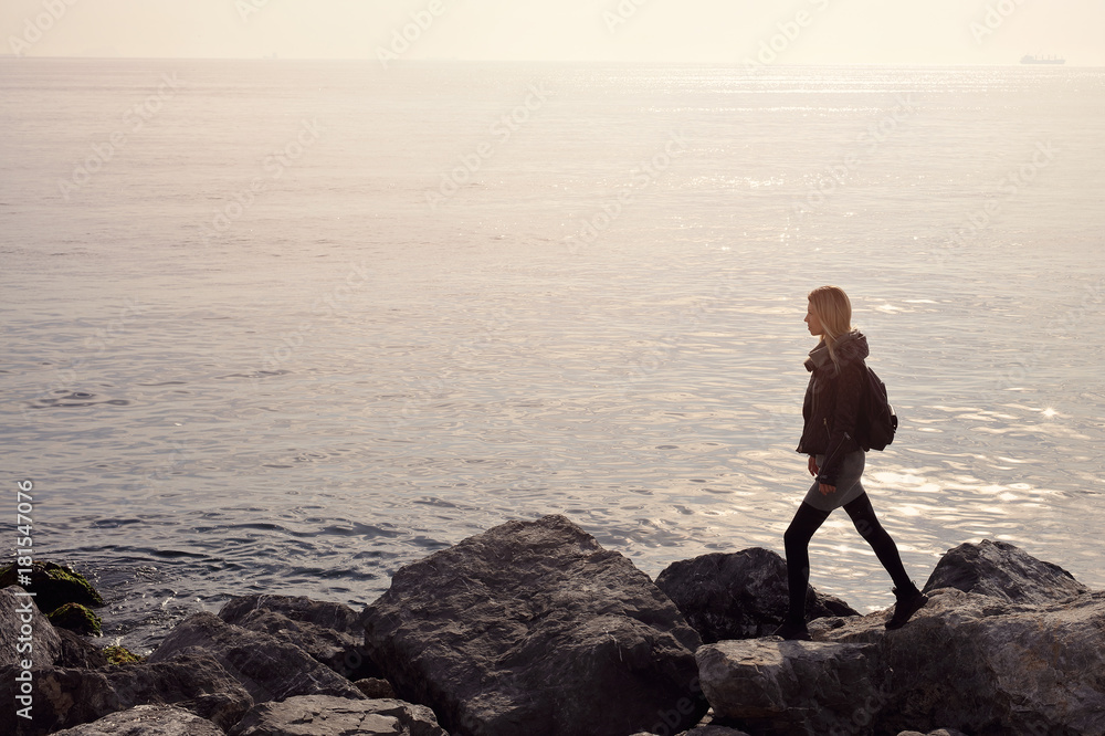 Young woman walking alone on stone sea coast. My dream, my goal , my way concept Young woman walking alone on stone sea coast. My dream, my goal , my way concept