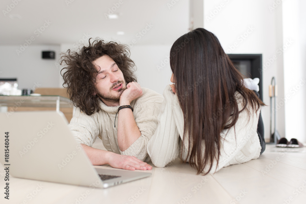 young multiethnic couple using a laptop on the floor young multiethnic couple using a laptop on the floor
