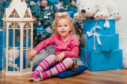 Blonde little girl sitting and smiling nearly decorated christmas tree  © k8most