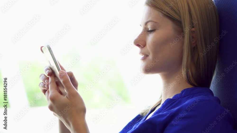 Woman tourist traveling on train. Using her smartphone, browsing, reading news, chatting with friends. Young female relaxing in high-speed international train. Slight natural shaking Woman tourist traveling on train. Using her smartphone, browsing, reading news, chatting with friends. Young female relaxing in high-speed international train. Slight natural shaking