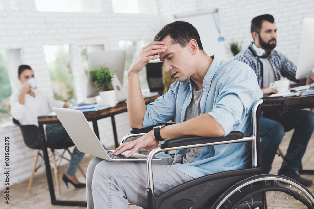 Disabled person in the wheelchair works in the office. He is sitting thoughtfully. Disabled person in the wheelchair works in the office. He is sitting thoughtfully.