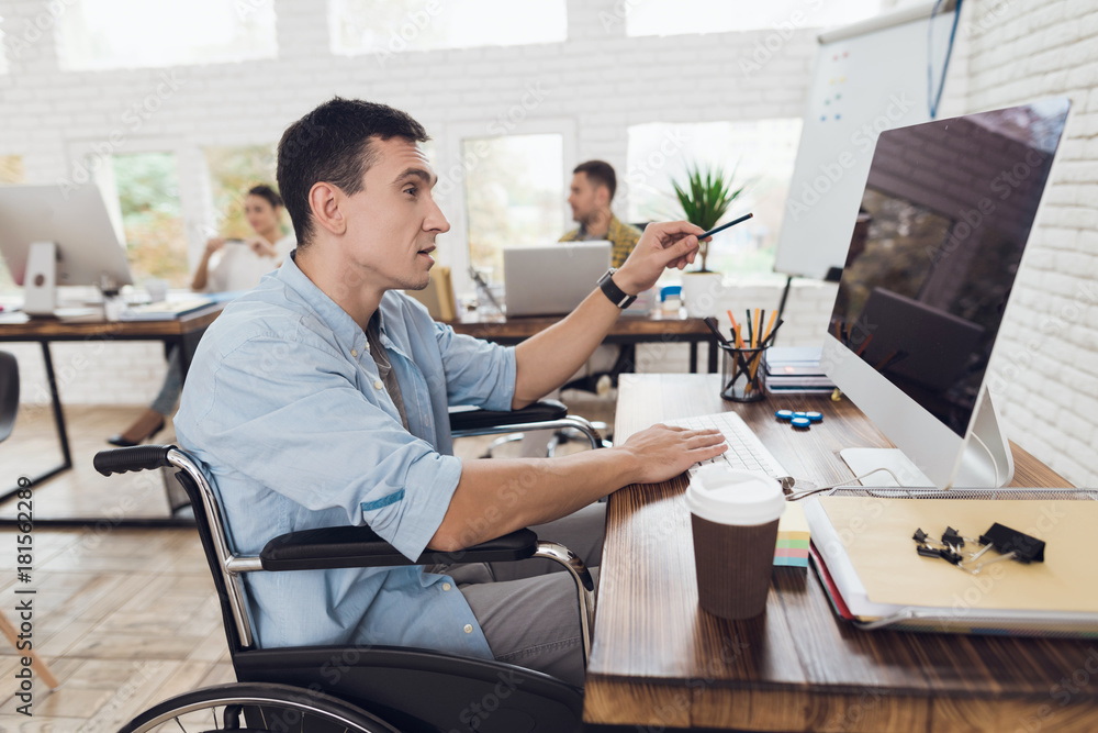 Disabled person in the wheelchair looks carefully at the computer.