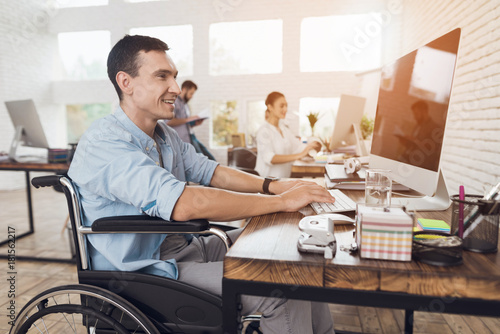 Disabled person in the wheelchair works in the office at the computer. © VadimGuzhva