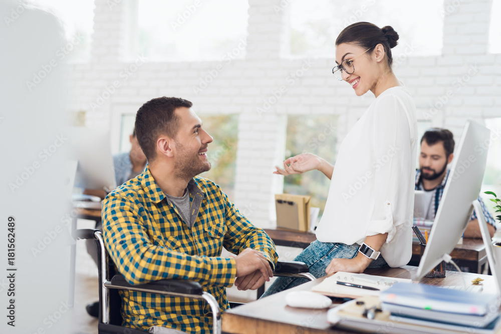 A man in a wheelchair talking to a young girl in a bright office. A man in a wheelchair talking to a young girl in a bright office.