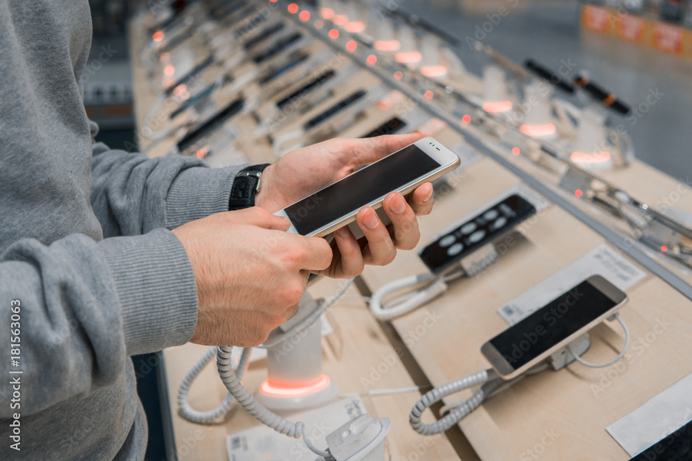 custom made wallpaper toronto digitalCloseup view of male customer hands, choosing white smartphone in the mobile phone store. difficult decision. Various choice