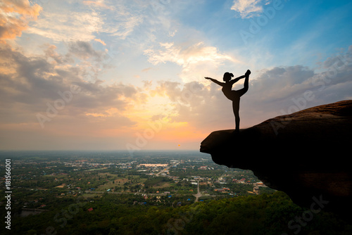 Silhouette woman playing yoga on top of the mountain at sunset