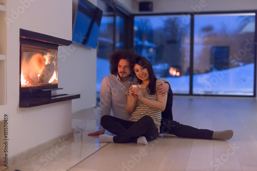 happy multiethnic couple sitting in front of fireplace