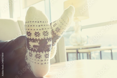 Person relaxing in Christmas themed socks indoors