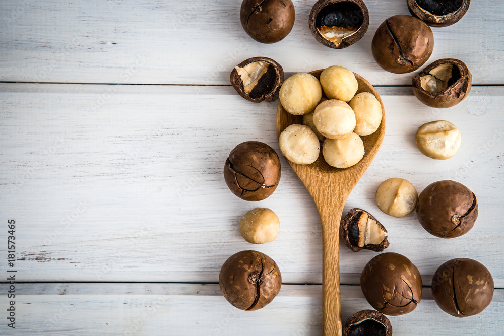 Close up Macadamia nuts on white wooden background , the superfood and healthy food concept , overhead or top view shot with vintage color tone Close up Macadamia nuts on white wooden background , the superfood and healthy food concept , overhead or top view shot with vintage color tone