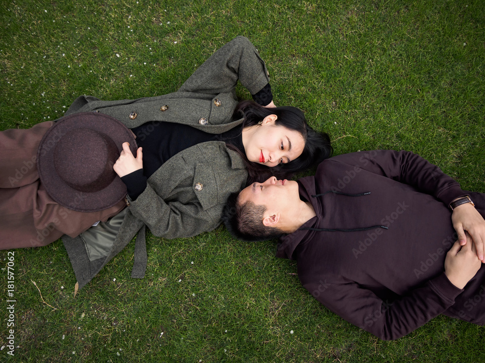 High angle view of couple of Chinese young people lying on green grass field and looking each other full of love, lover concept. High angle view of couple of Chinese young people lying on green grass field and looking each other full of love, lover concept.