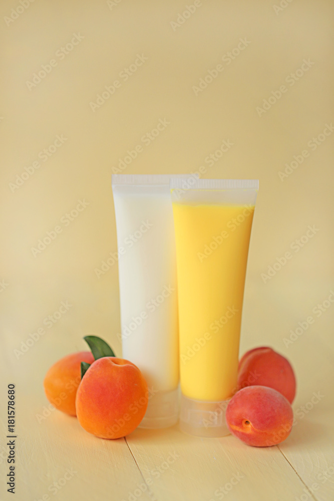 cosmetic with apricot . yellow apricot shower gel and white body cream with apricot extract and apricots fruit on a yellow wooden background. organic cosmetic cosmetic with apricot . yellow apricot shower gel and white body cream with apricot extract and apricots fruit on a yellow wooden background. organic cosmetic