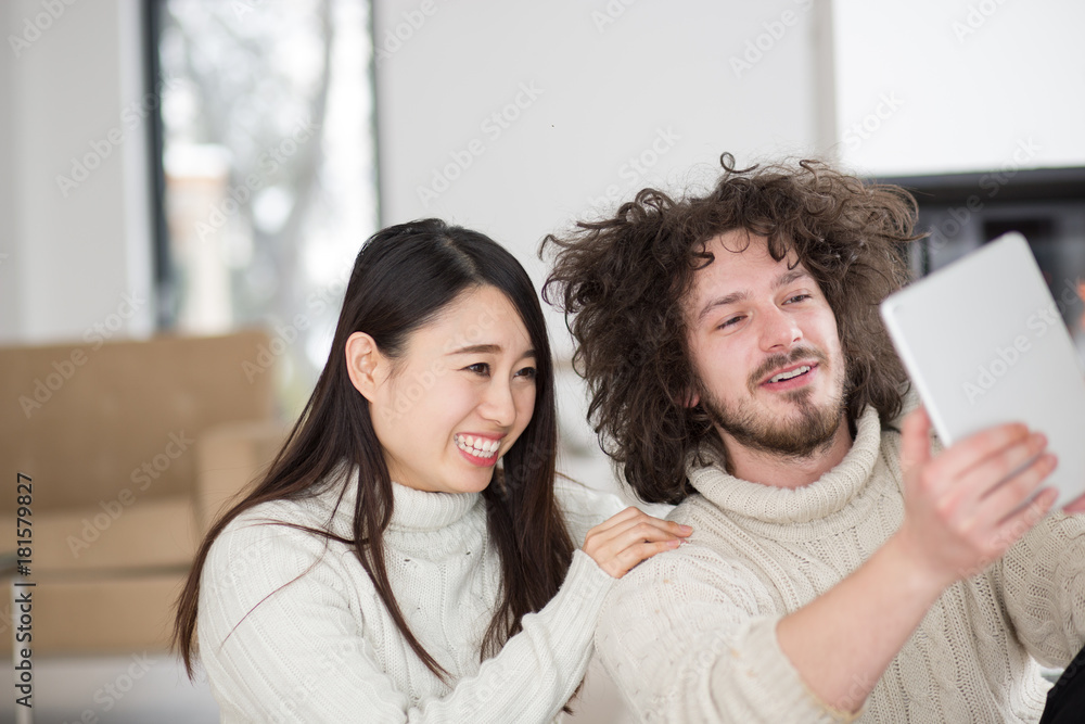 multiethnic couple using tablet computer in front of fireplace multiethnic couple using tablet computer in front of fireplace